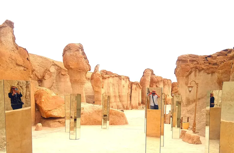 Visitors walking between the shaded sandstone clefts of Al-Qarah Mountain in the Al-Ahsa oasis, eastern Saudi Arabia.