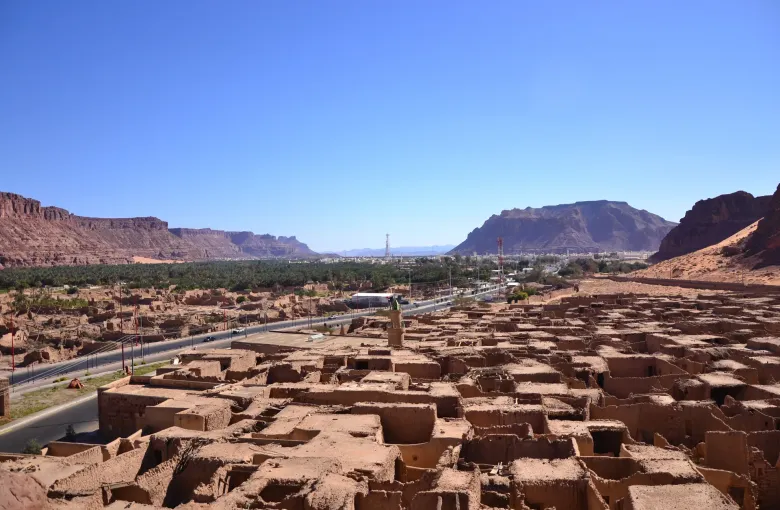 The AlUla valley in north-west Saudi Arabia, its ruined mud-brick town in the foreground and sandstone cliffs closing the horizon.