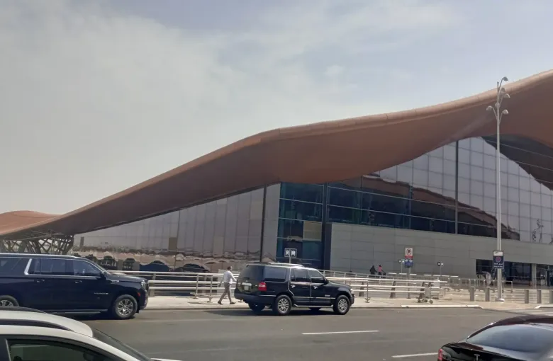 The curved roof of the terminal at King Abdulaziz International Airport in Jeddah, Saudi Arabia, with cars waiting at the kerb.