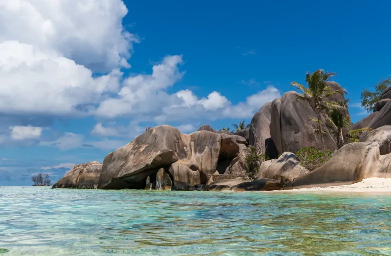 Weathered granite boulders standing in shallow turquoise water at Anse Source d'Argent on La Digue, Seychelles.