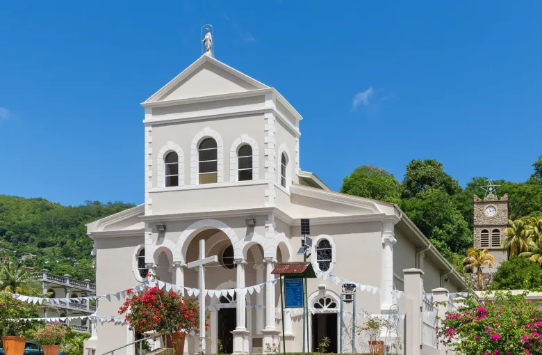 The white Cathedral of the Immaculate Conception in Victoria, hung with bunting, its detached clock tower and bougainvillea beside it.