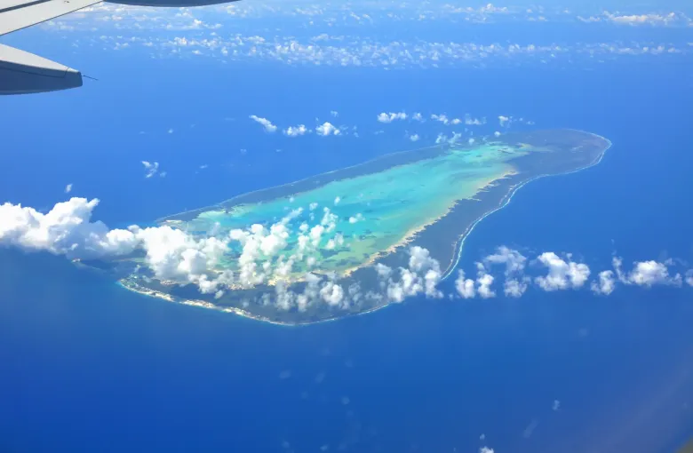 A low coral island and its pale lagoon set in deep blue ocean, seen from an aircraft over the outer islands of Seychelles.