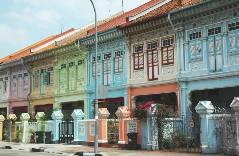 A terrace of pastel Peranakan shophouses with ornamented windows and gates on Koon Seng Road, Singapore.