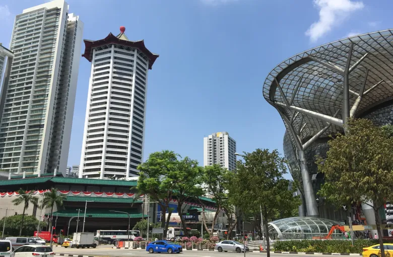 Traffic on Orchard Road in Singapore passing beneath an Electronic Road Pricing gantry, with malls and trees behind.