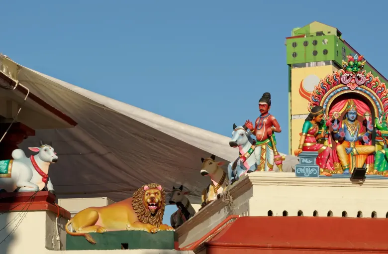 Painted sculptures of deities and a seated bull along the roofline of the Sri Mariamman Temple in Singapore's Chinatown.