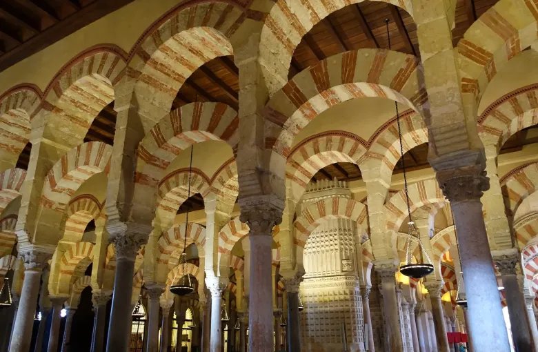 Red and cream striped double arches on marble columns in the hypostyle hall of the Mosque-Cathedral of Cordoba, Spain.