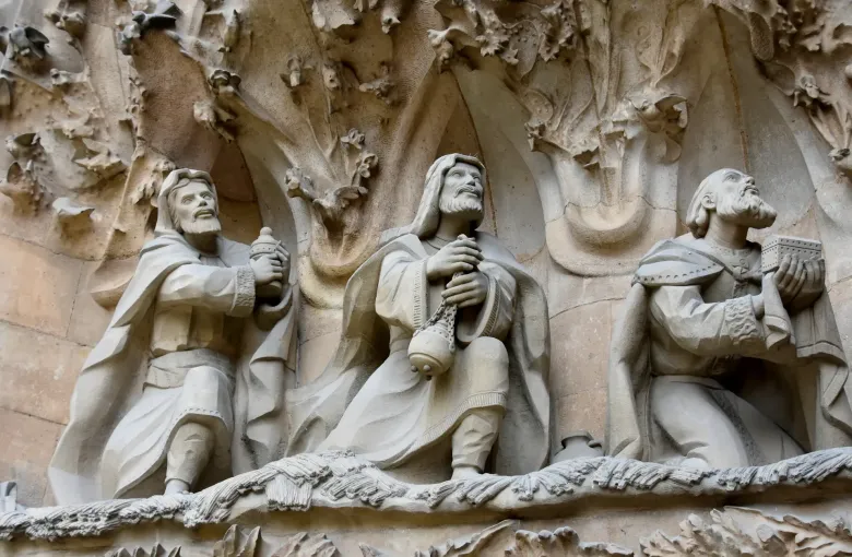 Carved stone figures of the Magi bearing gifts on the Nativity facade of the Sagrada Familia in Barcelona, Spain.