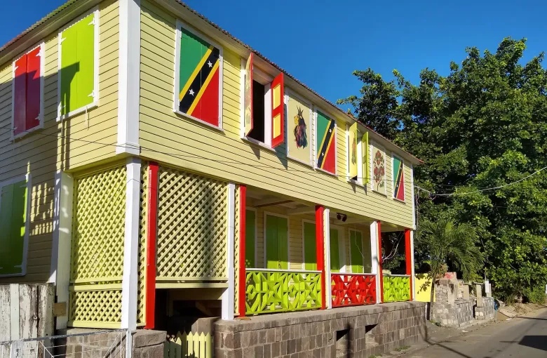 A wooden house in Basseterre with the St Kitts and Nevis flag painted across several of its shutters.