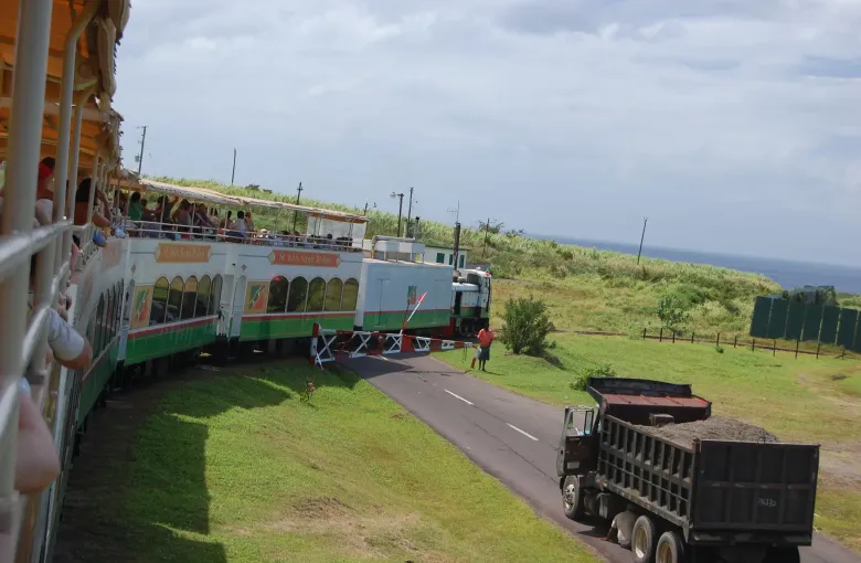 Double-deck carriages of the St Kitts Scenic Railway on the old sugar line, passengers seated above.