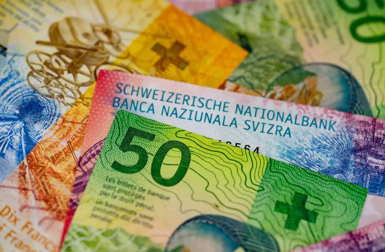 Swiss franc banknotes overlapping, a green fifty-franc note on top carrying the name of the national bank in four languages.