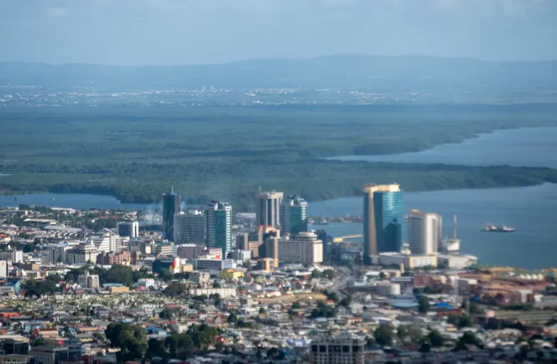 The waterfront towers of Port of Spain above the Gulf of Paria, with mangroves and hills beyond.
