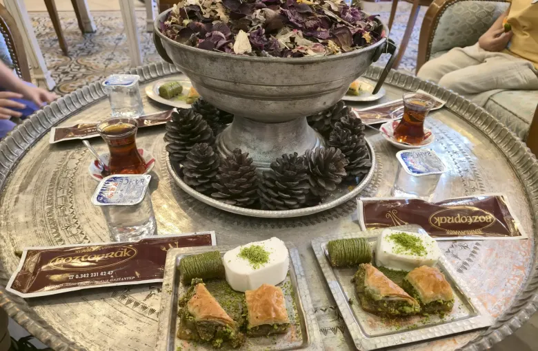 A tray of baklava in several varieties served with tulip glasses of Turkish tea.