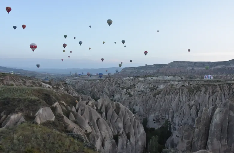 Balloons scattered above the eroded tuff valleys of Goreme National Park in Cappadocia, Turkey, at first light.