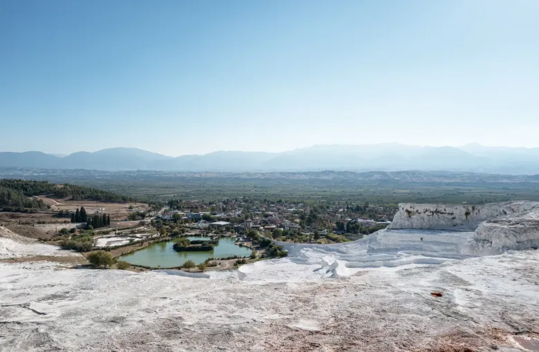 The white travertine terraces of Pamukkale in Denizli province, Turkey, stepping down towards the green valley below.
