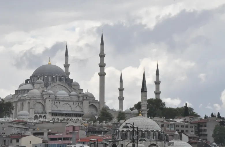 The Suleymaniye Mosque on its hill above the Golden Horn in Istanbul, Turkey, its cascading domes and four minarets against heavy cloud.