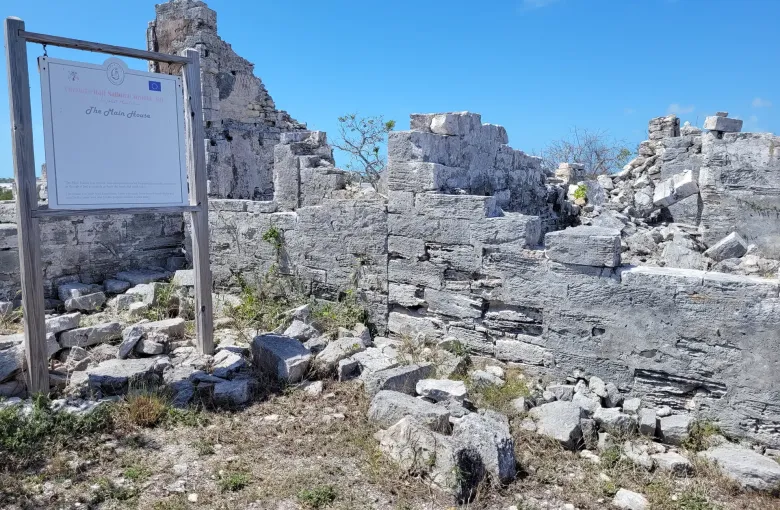 Roofless limestone walls of the main house at Cheshire Hall plantation on Providenciales, beside an information board.