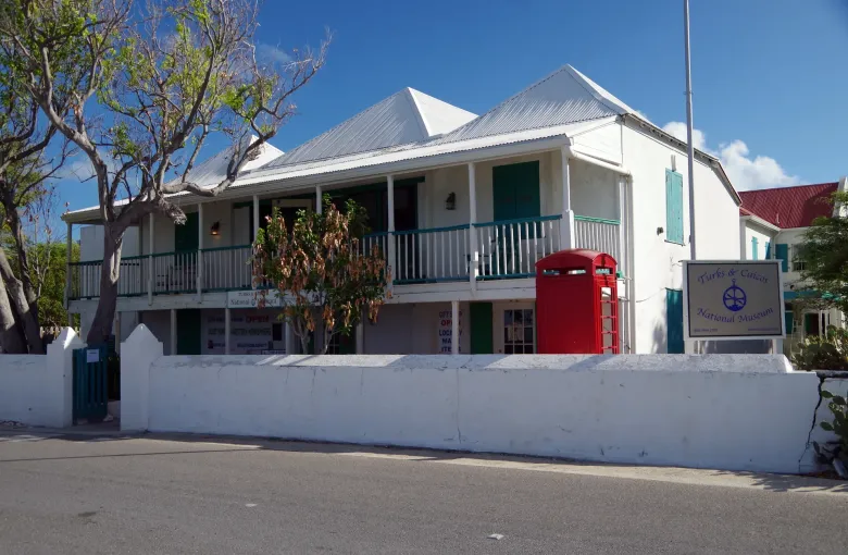 The National Museum on Grand Turk seen from the road, white walled with green shutters and a red telephone box.