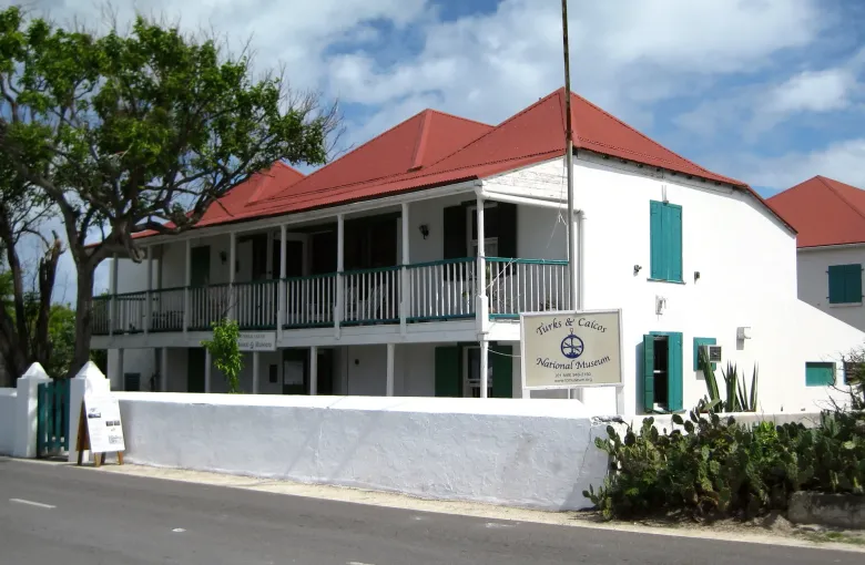 The white two storey National Museum on Grand Turk, red roofed with deep verandahs and its sign at the gate.