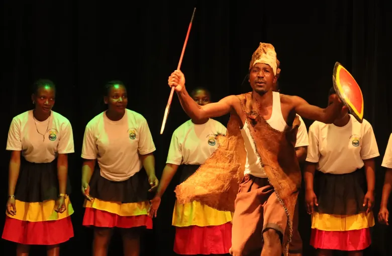 Dancers in yellow, black and red costume performing the ekitaguriro dance on a stage in Uganda.