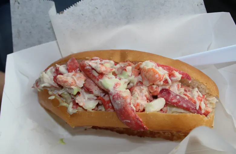 A split roll filled with dressed lobster meat, served in paper.