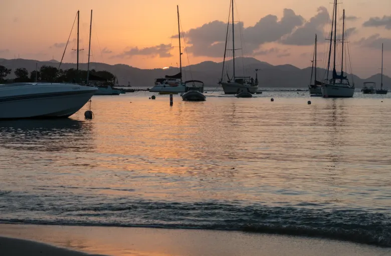 Sailing boats moored off Cruz Bay on St John at sunset, with the hills of the next island beyond.