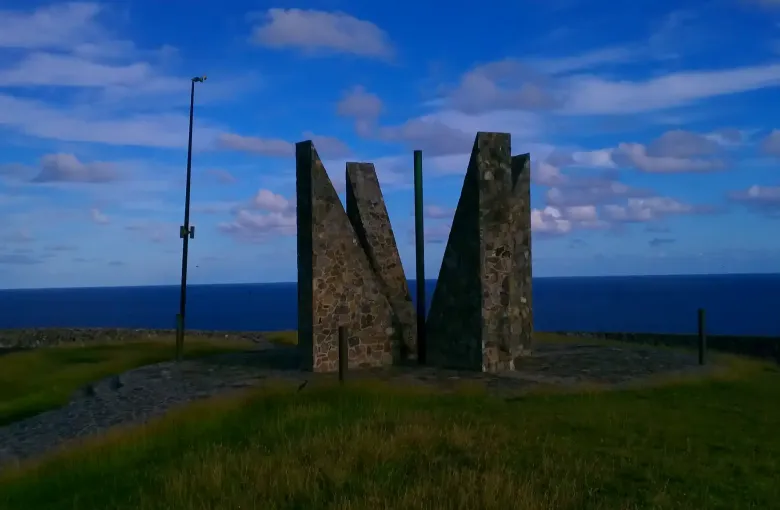 The stone millennium monument standing on the grass at Point Udall on St Croix above an open sea.