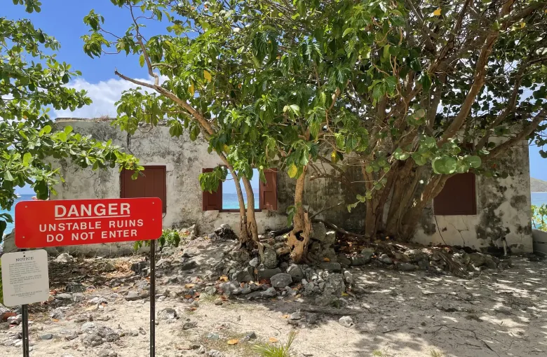 A red warning sign reading unstable ruins do not enter, in front of Danish warehouse ruins on St John.