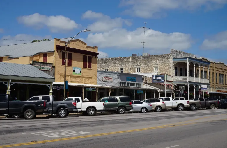 Nineteenth century limestone and painted storefronts with deep porches along Main Street in Fredericksburg, Texas.