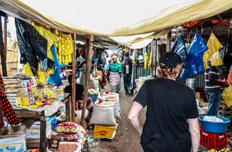 Sacks of dried beans and dried shrimp open along a covered market aisle in Vilankulo, packaged goods stacked on the stalls.