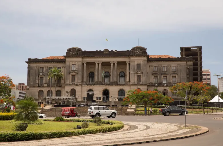 The city hall on Praça da Independência in Maputo, flame trees in flower and a broad paved apron in front.