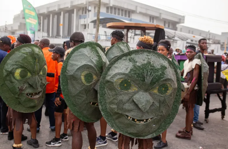 Performers in large carved masks among the crowd on a Calabar street during the carnival in Cross River State, Nigeria.