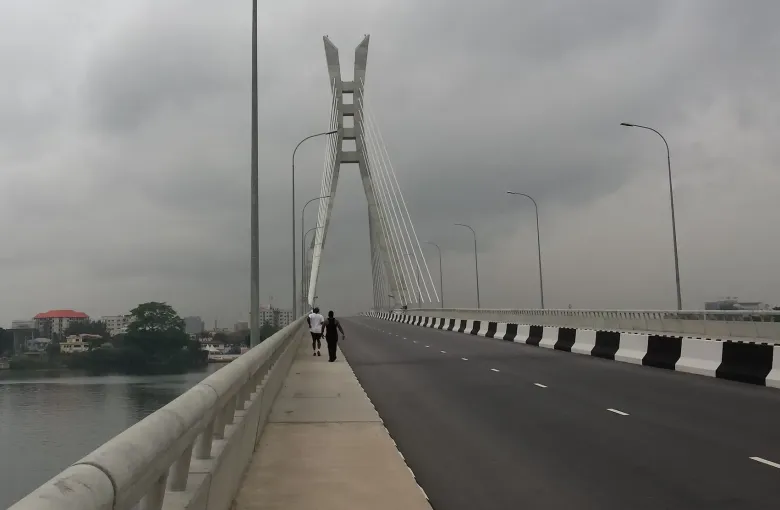 The cable-stayed Lekki Ikoyi link bridge over the lagoon in Lagos, Nigeria, with two people walking the footway.